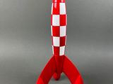 un gros plan d'une fusée jouet rouge et blanche posée sur une surface grise