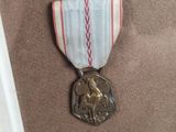 a silver medal with a red and white ribbon on it