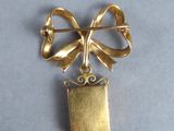 an image of a gold brooch with a bow on it