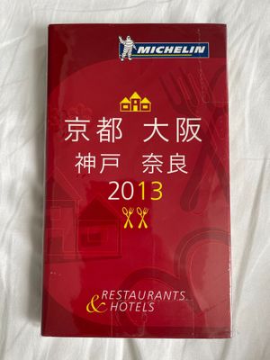 menu d'un restaurant chinois posé sur un lit aux draps blancs et à la couverture rouge