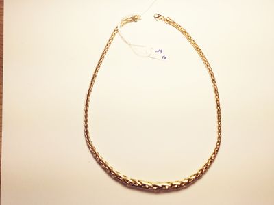 a close up of a gold necklace on a white surface