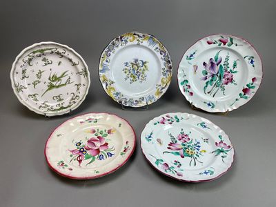 quatre assiettes ornées de motifs floraux sont disposées sur un fond gris