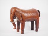 a small wooden elephant that is standing on a white surface