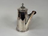 an antique silver coffee pot with a wooden handle on a white surface