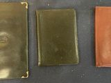 three different types of leather wallets sitting on top of a table