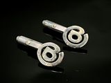 paire de boutons de manchette en argent sur un support noir avec un fond noir