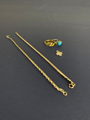 une chaîne en or ornée d'une perle turquoise côtoie une paire de boucles d'oreilles