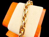 a gold bracelet with a gold chain on a wooden block