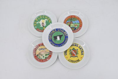 four white plates with different types of badges on them on a white surface