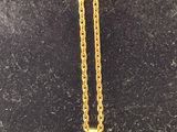 a gold necklace with a cross on it sitting on a black surface