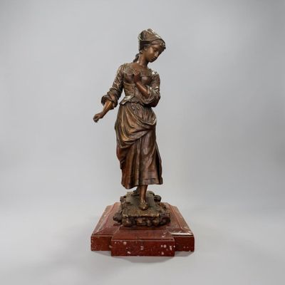 an antique bronze statue of a woman holding a bird on a wooden base