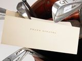 a card in a bag with golf clubs and a pair of irons