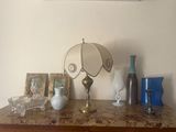 a table with a lamp, vases, and pictures on it