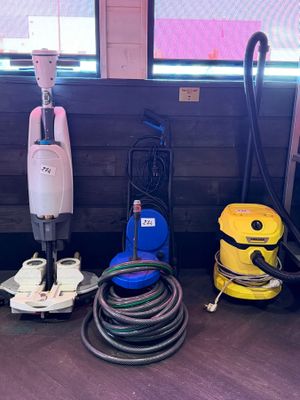 several vacuums and other cleaning equipment are lined up against a wall