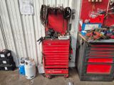 une armoire à outils rouge, sur laquelle sont posés des outils, dans un garage