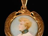 Un portrait ancien représentant une femme en robe blanche est représenté sur un pendentif plaqué or.
