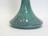 a green vase that is sitting on a white table