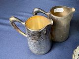 a silver pitcher and a silver plate on a blue cloth