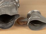 two silver vases sitting on a wooden table