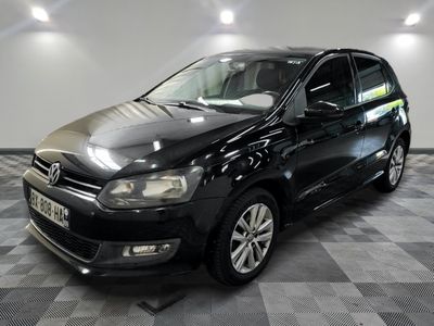 La Volkswagen Polo noire est garée dans une pièce au sol carrelé.