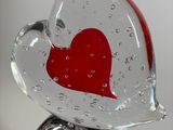 a glass sculpture of a red heart on top of a rock