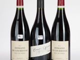 trois bouteilles de vin rouge posées l'une à côté de l'autre sur une surface blanche