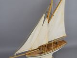wooden model of a sailboat with white sails on a wooden stand