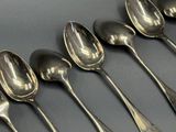 six cuillères en argent sont alignées sur une table