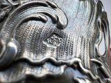 a close up of a silver vase with a bird on it