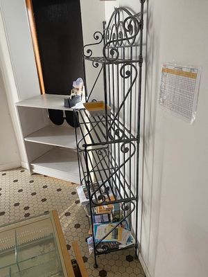 une étagère en métal sur laquelle est posée une horloge, dans une pièce
