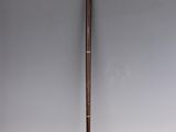 an old cane with a wooden handle sitting on a white surface