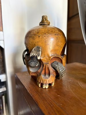 a wooden skull on a shelf next to a book shelf