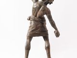 a bronze statue of a man holding a baseball bat on top of a wooden base