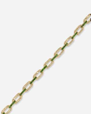 un gros plan sur un bracelet en or orné de pierres vertes et blanches