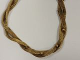 gros plan d'un bracelet en or sur une surface blanche