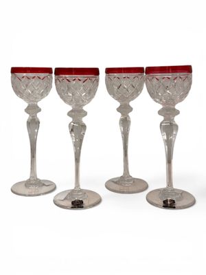 four wine glasses with red rims are lined up on top of each other
