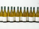 six bouteilles de vin blanc alignées sur une surface blanche