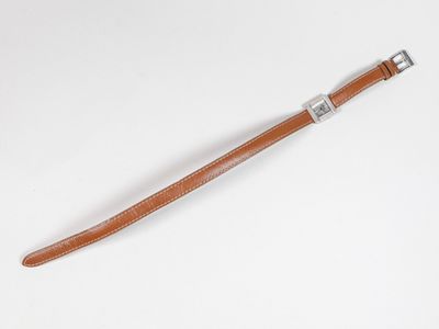 un gros plan d'un bracelet en cuir marron sur une surface blanche
