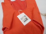 an orange t - shirt with a tag on it sitting on a table