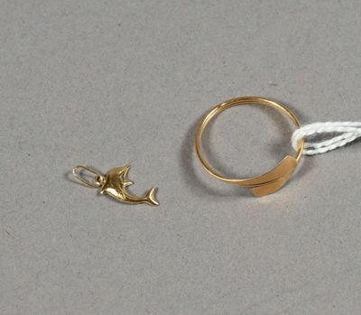 une bague en or ornée d'un poisson, à côté d'un cordon blanc