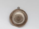an old silver metal strainer on a white surface