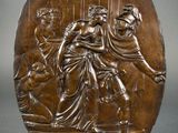 a bronze plaque depicting a woman and two men on a stage