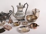 a silver tea pot and other silver objects on a white surface