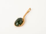a close up of a green stone on a gold plated spoon