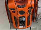 un souffleur orange posé sur un mur, près d'une fenêtre