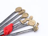 several swords with gold and red handles on a white surface