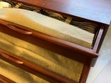 a wooden dresser with three drawers and a rug on top of it