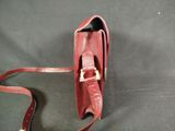 someone is holding a red purse on a black surface
