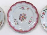 three plates with floral designs are lined up on a white surface