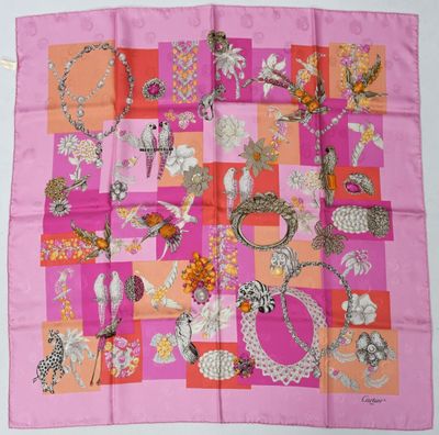 un gros plan d'un foulard carré rose et orange posé sur une table